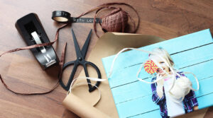 Ein Leinwandbild liegt auf Packpapier. Daneben liegt eine Schere, Klebeband, Geschenkband und Washi Tape.